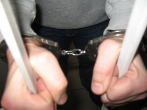 Ręce w kajdankach trzymają kraty w areszcie.