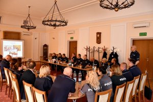 Polscy i litewscy policjanci siedzą w sali zegarowej na spotkaniu w komendzie policji.
