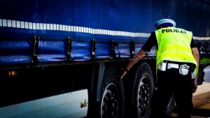 policjant ruchu drogowego podczas sprawdzania ogumienia pojazdu ciężarowego