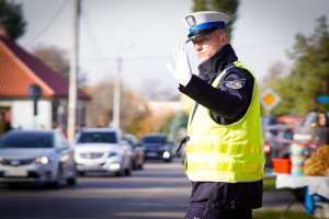 policjant ruchu drogowego, ubrany w żółtą odblaskową kamizelkę, który kieruje ruchem drogowym