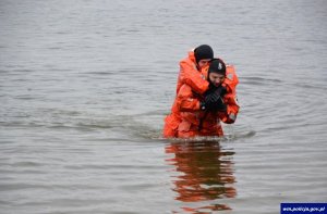 mężczyźni ubrani w pomarańczowe kombinezony wychodzą z wody