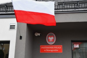 Flaga Polki na tle napisu Posterunek Policji w Nowogrodzie