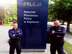 Policjanci stoją przy tablicy z napisem Komenda Powiatowa Policji w Hajnówce