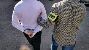 dwaj mężczyźni jeden na ręku posiada opaskę z napisem policja
