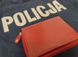 Napis policja na ubraniu i czerwony portfel.