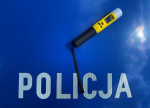 na niebieskim tle napis policja i urządzenie do badania stanu trzeźwości