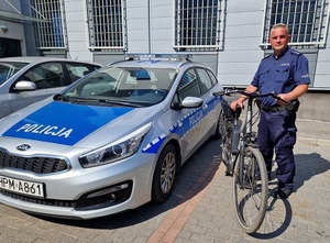 Policjant z rowerem przy radiowozie