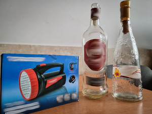 na stole stoją dwie szklane butelki i pudełko na którym widnieje zdjęcie latarki